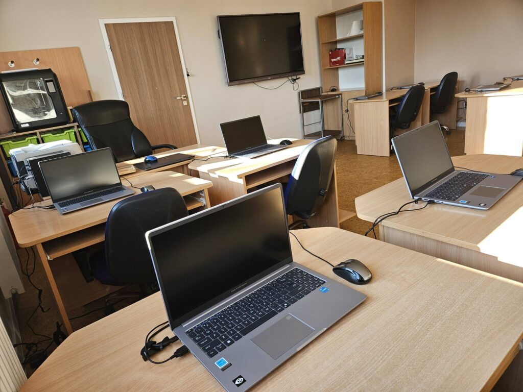 Zdjęcie przedstawia salę informatyczną z nowymi laptopami.