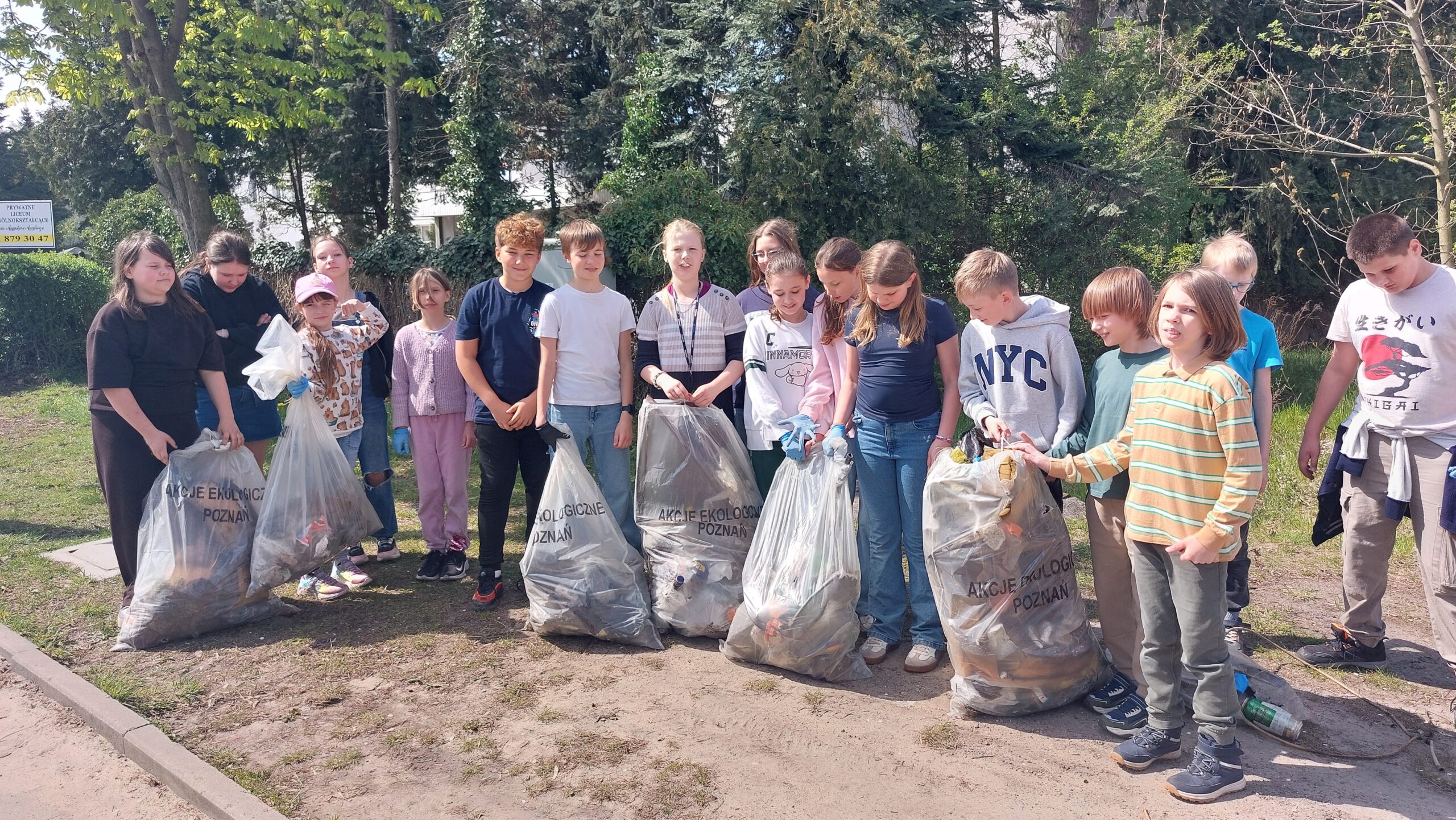 Zdjęcie przedstawia uczniów biorących udział w akcji sprzątania okolic szkoły.